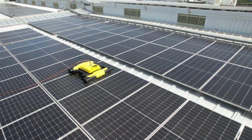 E1 Pro robot clearing dust from a rooftop solar array, cable trailing behind it
